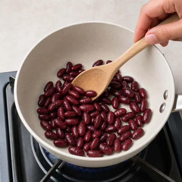 Gros plan pédagogique de réchauffe doucement 80 g de haricots rouges sans les écraser. Montrer le récipient exact, une main adulte avec l'ustensile adapté et la couleur ou texture qui prouve la cuisson. Aucun autre aliment ne doit masquer le résultat.